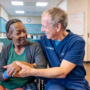 Surgeon and patient sitting together smiling.